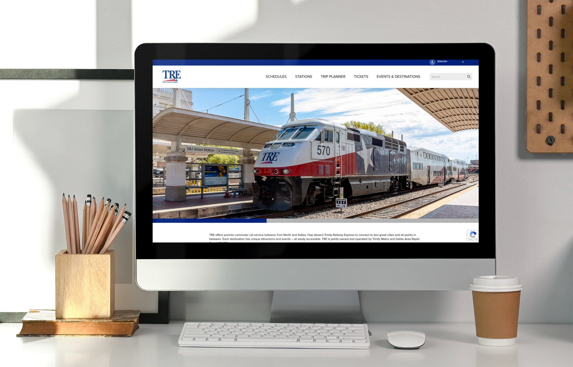 A computer monitor displays the TRE (Trinity Railway Express) website, featuring a passenger train at a station platform as the main image.