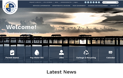 St. Johns County website homepage showing a pier at sunset, navigation menu, welcome message, and icons for permit status, bill payment, jobs, garbage, recycling, and calendar.