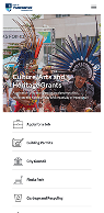 A webpage displays Cultural and Heritage Grants information with a photo of people in colorful feathered headdresses at a festival and menu options below.