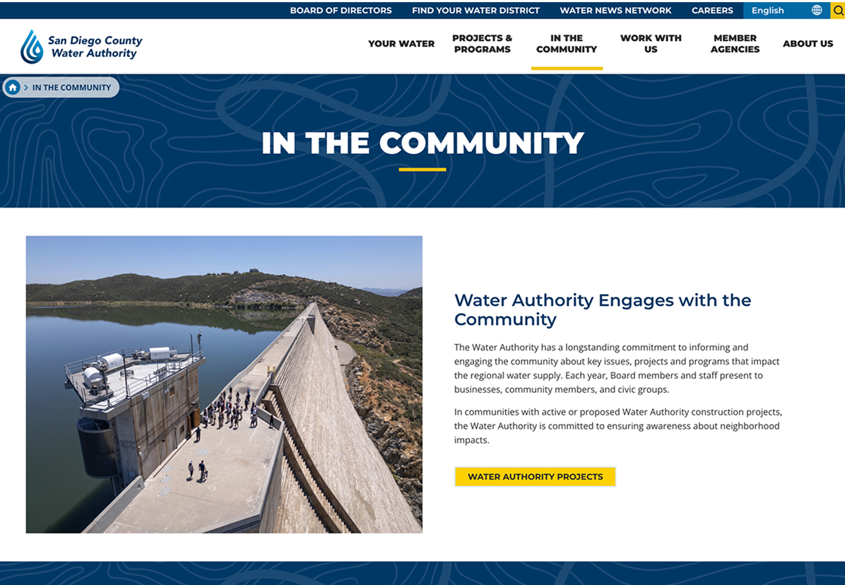 Aerial view of a large dam with water on one side, blue sky above, and a small building beside the dam; website text discusses community engagement by the San Diego County Water Authority.