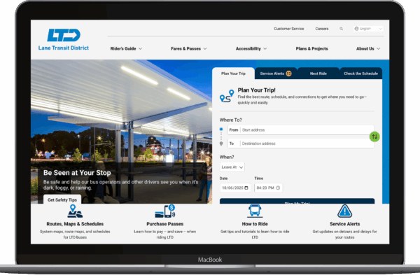 A laptop displays the Lane Transit District website featuring trip planning options, route information, and rider alerts against a background image of a transit stop at dusk.