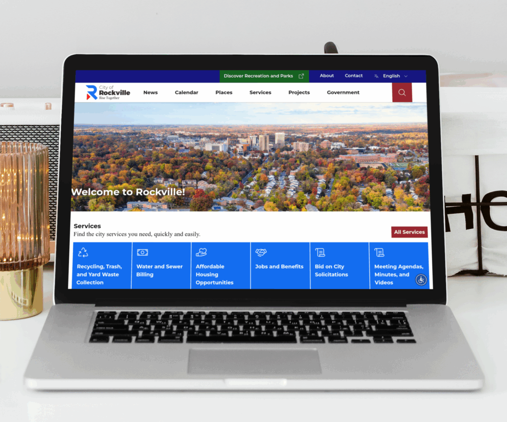 A laptop displays the City of Rockville website homepage, featuring a city aerial photo, navigation menu, service icons, and main sections in blue and white.